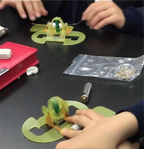 図６　良く回せている子（手前）と，なかなか回らなくて苦労している子（奥）が，教え合いながら製作している様子。